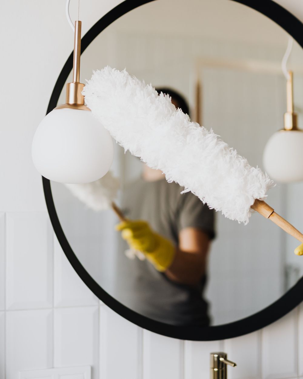 A bathroom mirror being dusted during a clean
